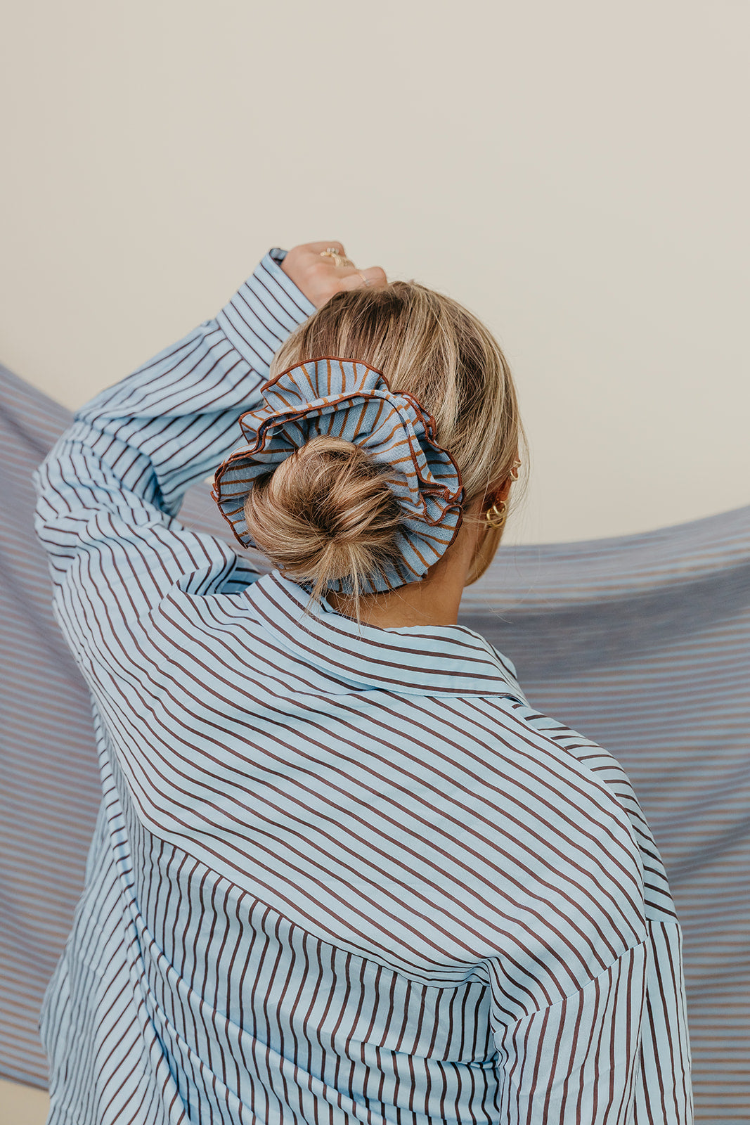 Blue and brown striped corset-style scrunchie on blonde hair bun from behind