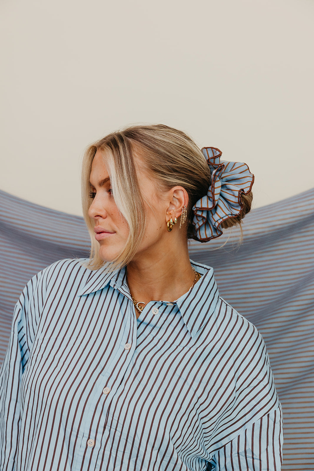 Blue and brown striped corset-style scrunchie worn on blonde hair bun