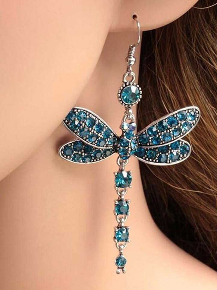 Dragonfly drop earring worn on an ear, with blue stones and a silver-tone setting