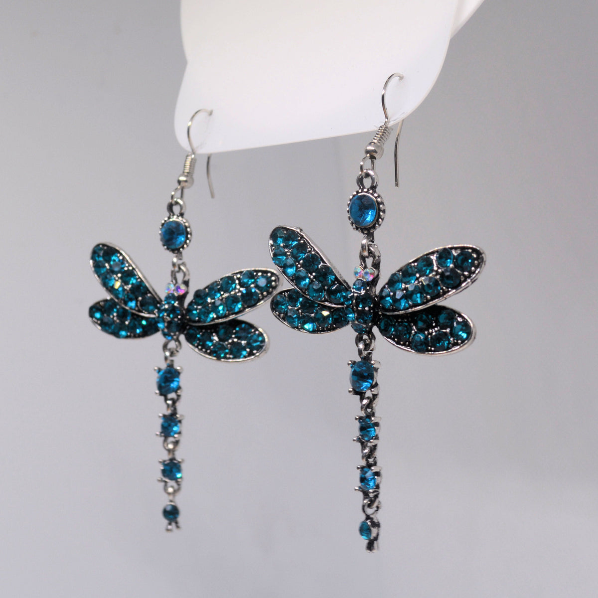 Dangling dragonfly earrings with glittering blue wings and linked stone details