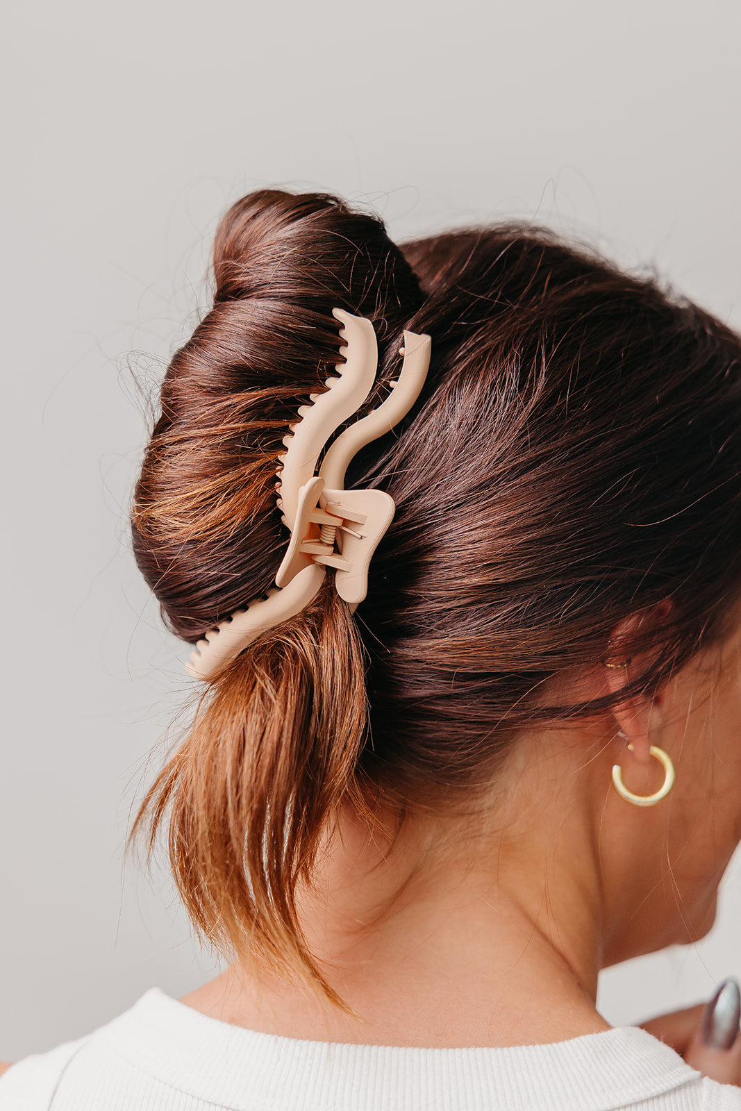 Beige wavy claw hair clip in an updo bun