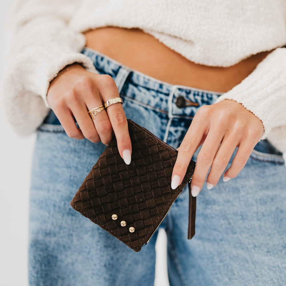 Woven suede wallet in dark brown with snap studs and gold tassel zipper pull.