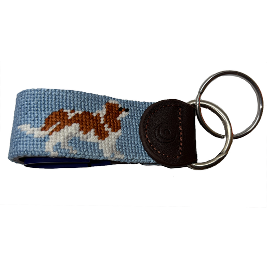 Blue needlepoint key fob with brown leather strap and metal key ring