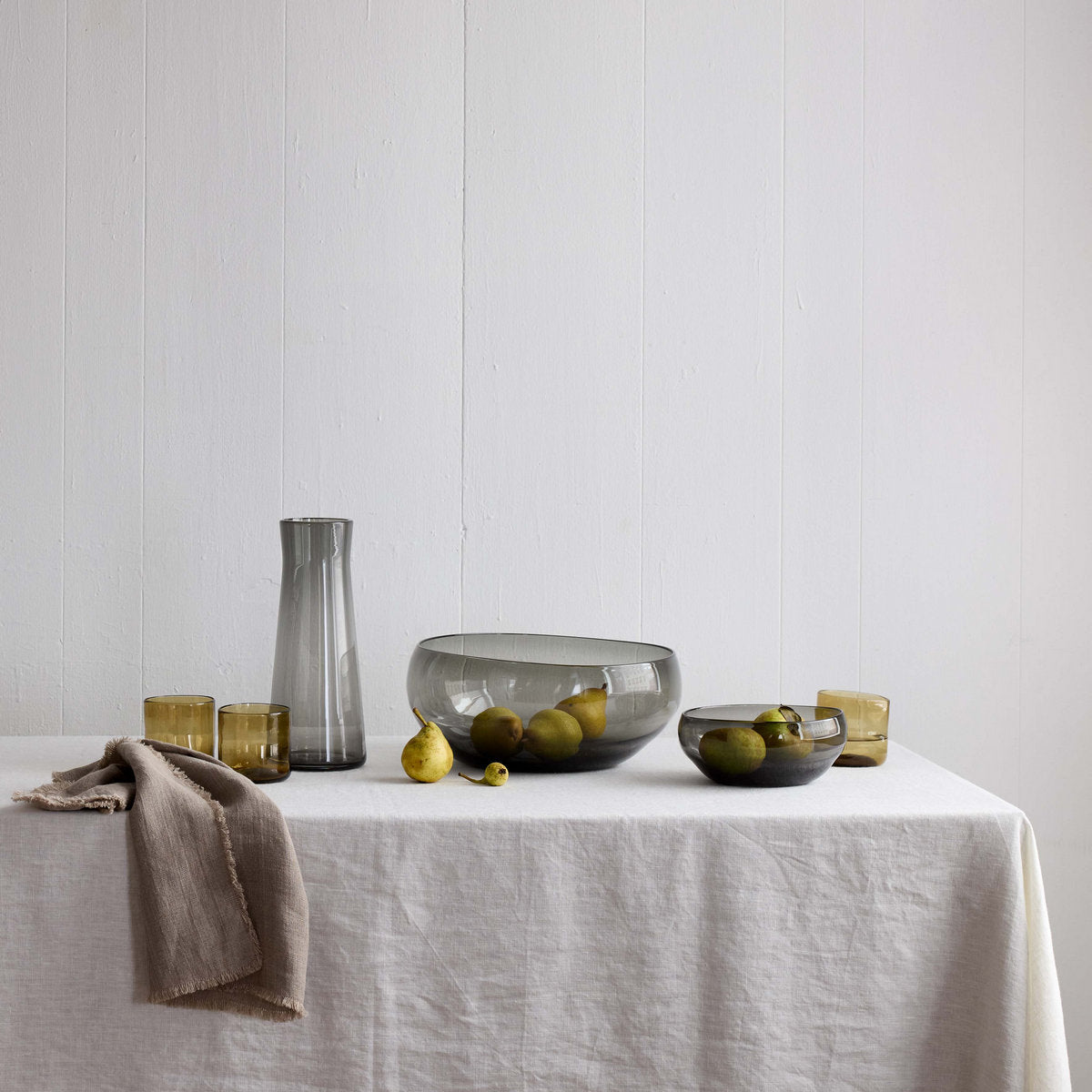 Light gray linen tablecloth laid across a dining table with serving dishes