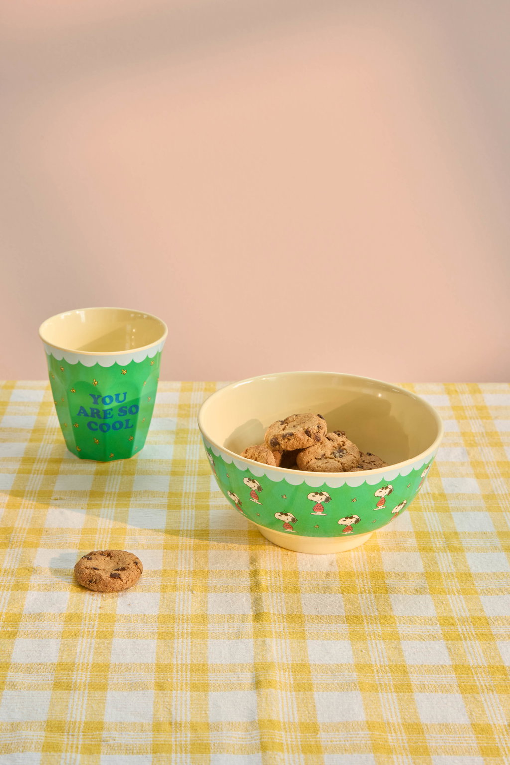 Green melamine cup with Snoopy graphic, shown with snacks on a table