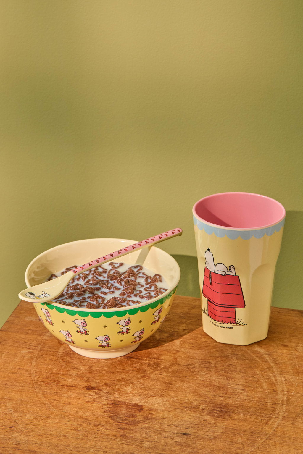 Yellow bowl with green scalloped border and Peanuts-style character print.