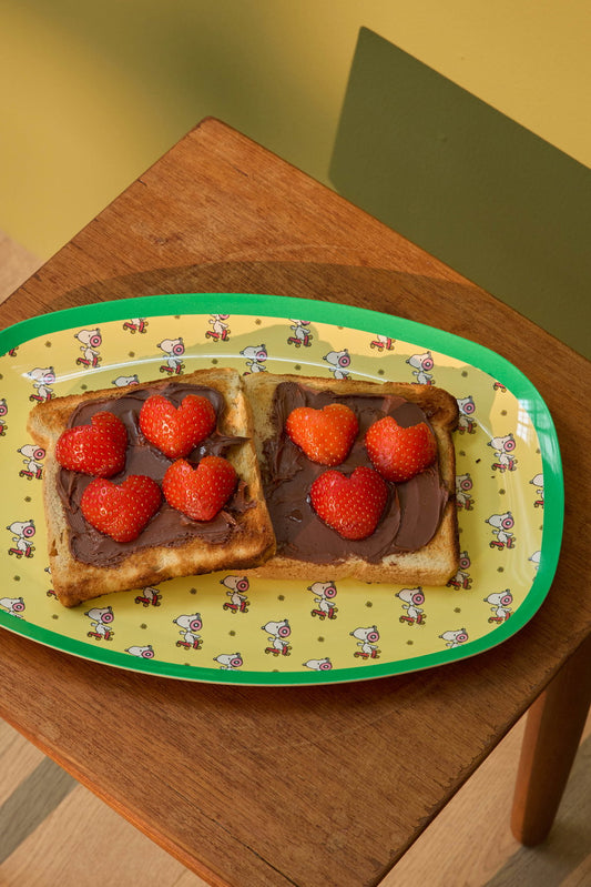 Yellow oval Snoopy print plate with green edge, holding toast and strawberries