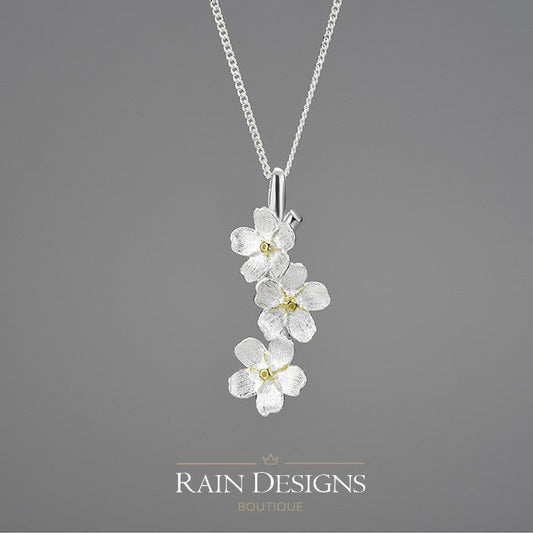 Silver forget-me-not flower necklace with three dangling blossoms and chain link collar.