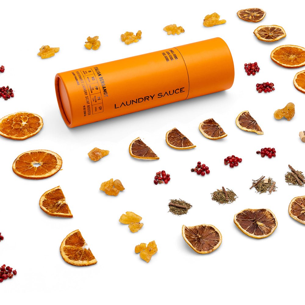 Orange cylinder laundry scent booster with citrus slices and dried spice pieces