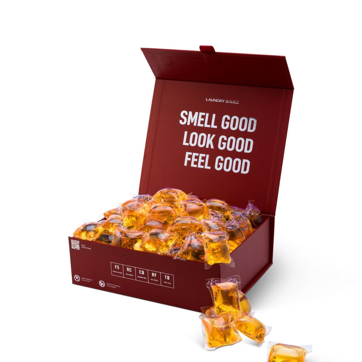 Laundry detergent pod box open with orange gel pods and a loose pod in front