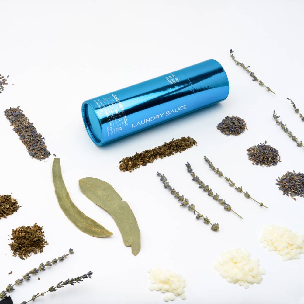 Blue cylinder laundry scent booster with dried herbs and small pale flower clusters