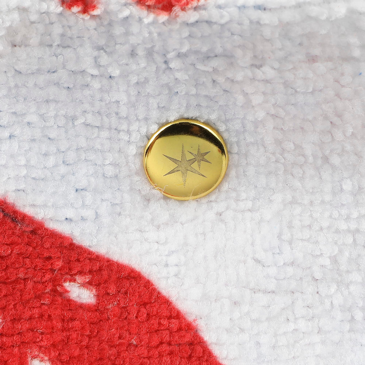 Round gold snap button on white towel tote bag with red and blue strawberry fabric