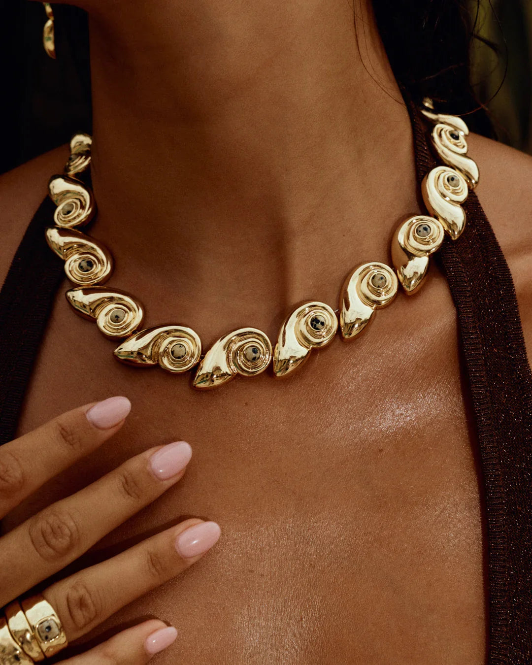 Gold statement necklace with spiral shell-like discs and curved links