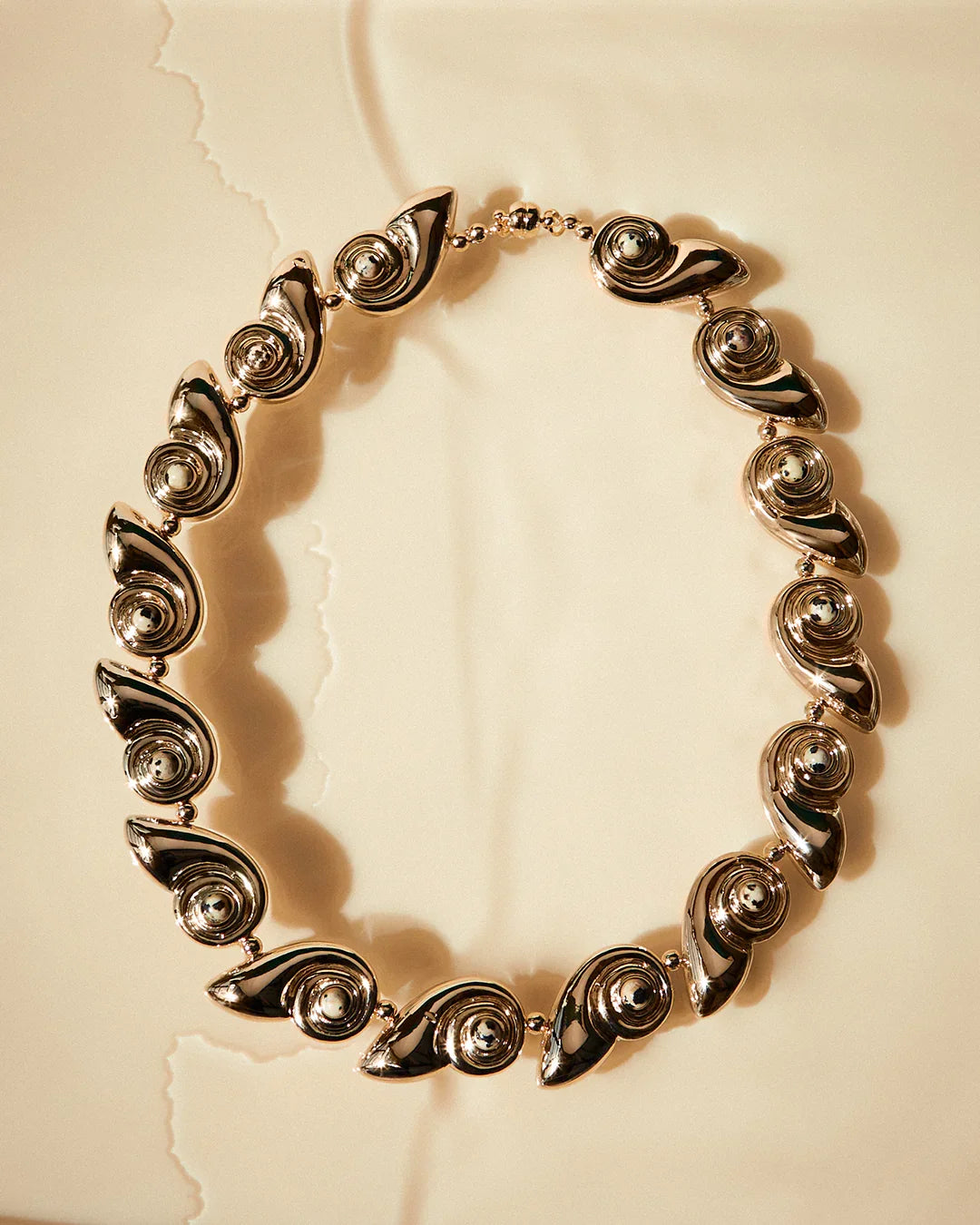 Gold statement necklace with spiral shell discs forming a continuous loop