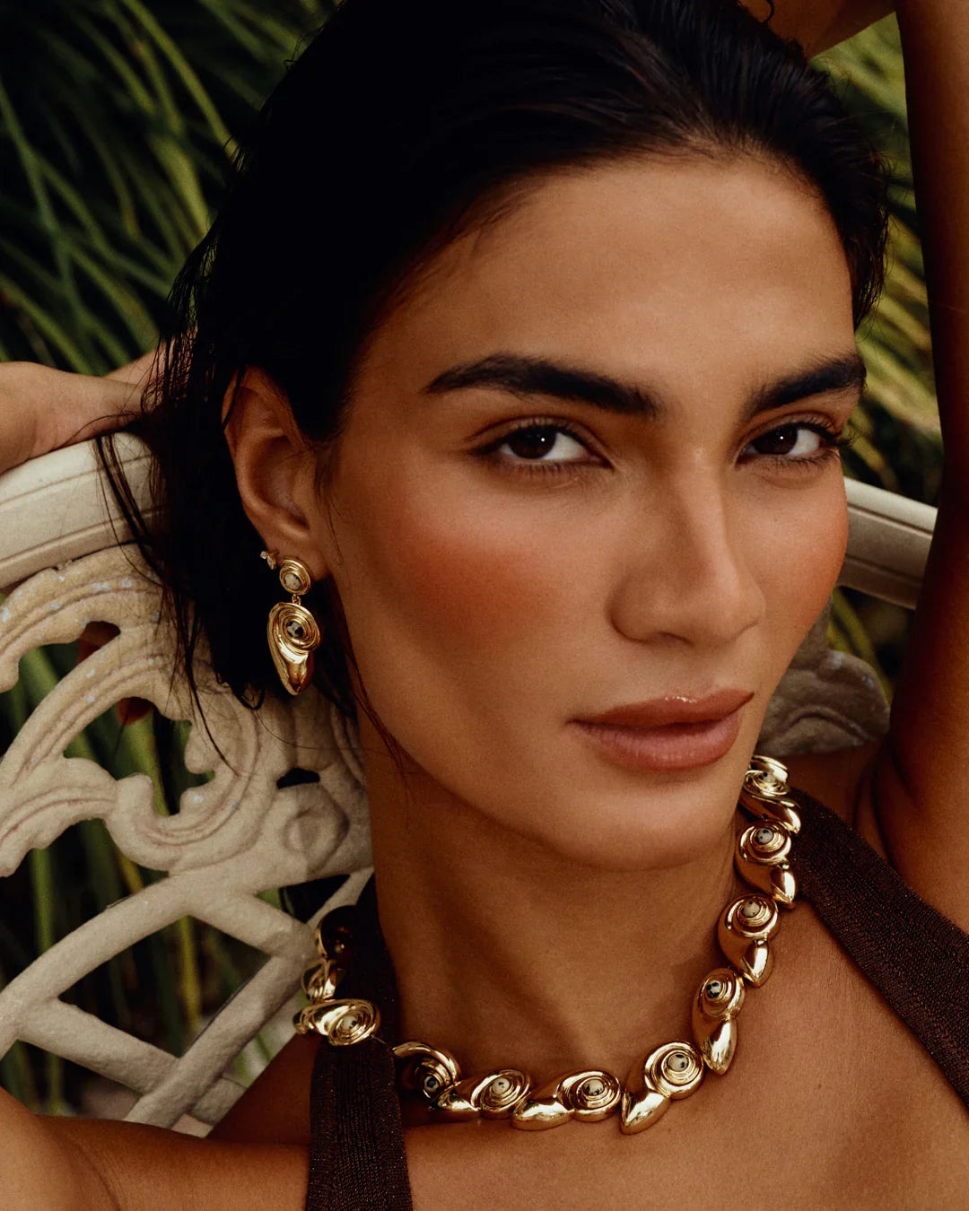 Gold statement necklace worn at collarbone with spiral shell-disc links