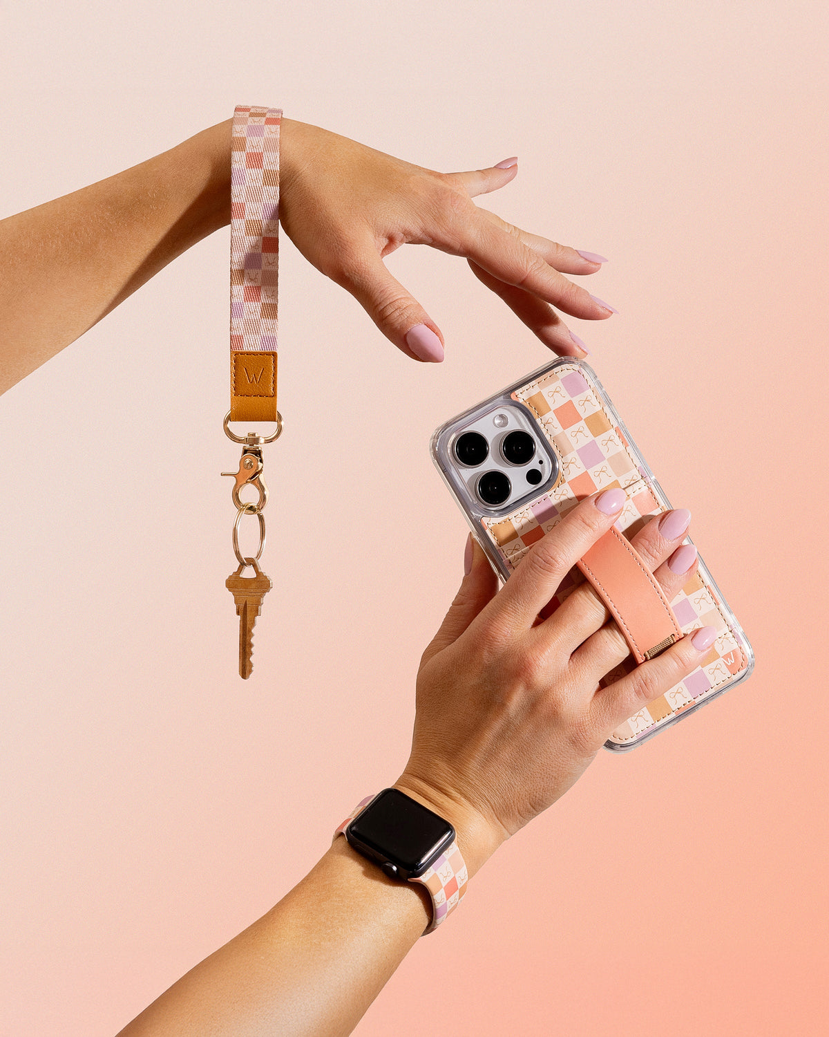 Phone case with peach bow pattern and tan strap, held in one hand