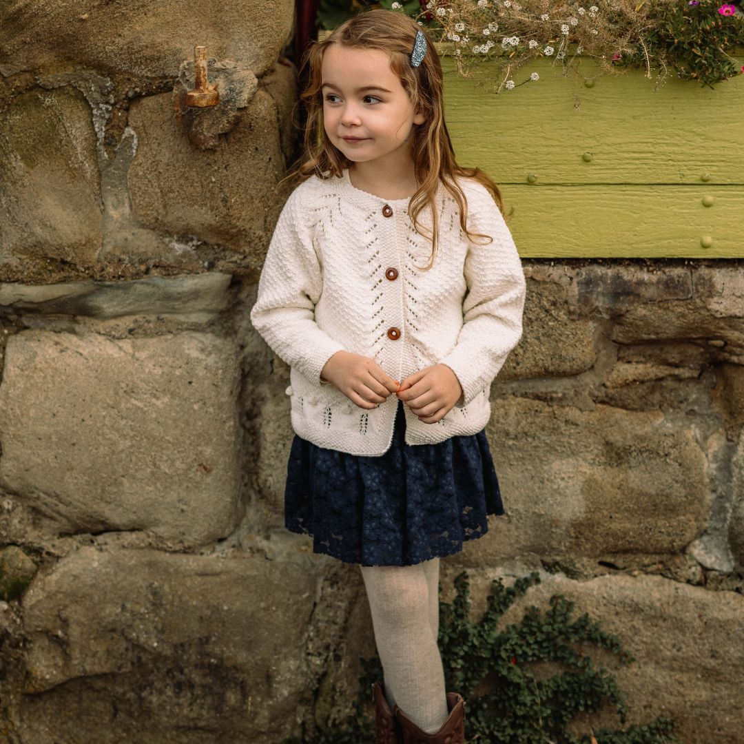 Cream knit cardigan with button front, long sleeves, and textured pattern