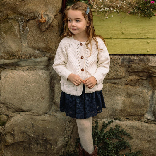 Cream knit cardigan with button front, long sleeves, and textured pattern