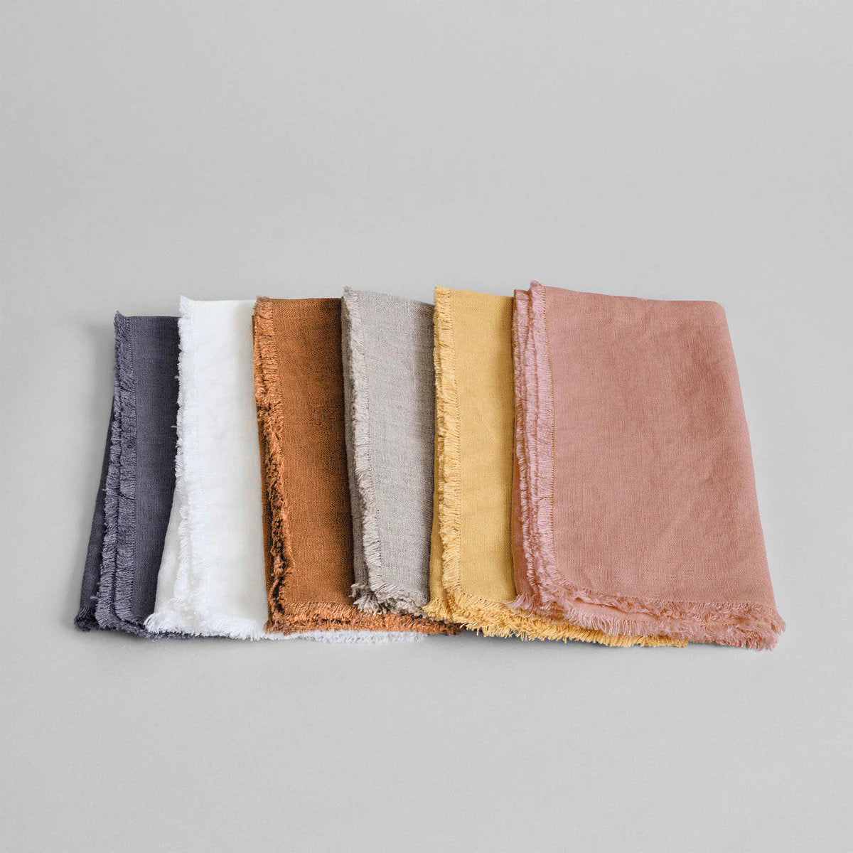 Set of fringed linen napkins in multiple colors, stacked and folded neatly