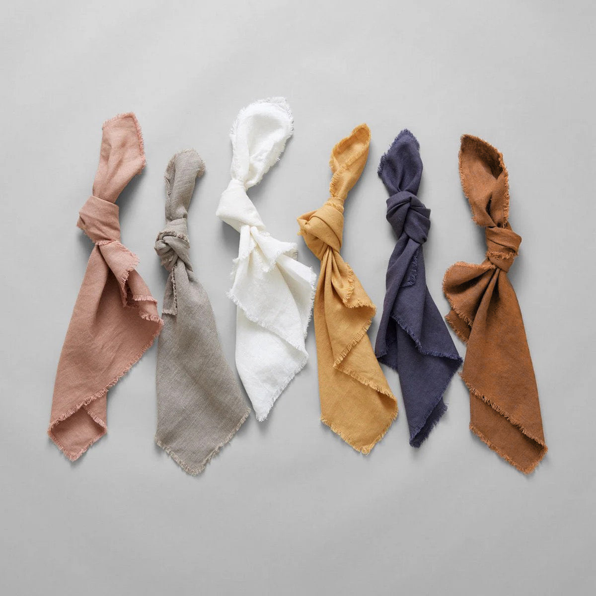 Fringed linen napkins set in assorted colors, neatly folded with frayed edges