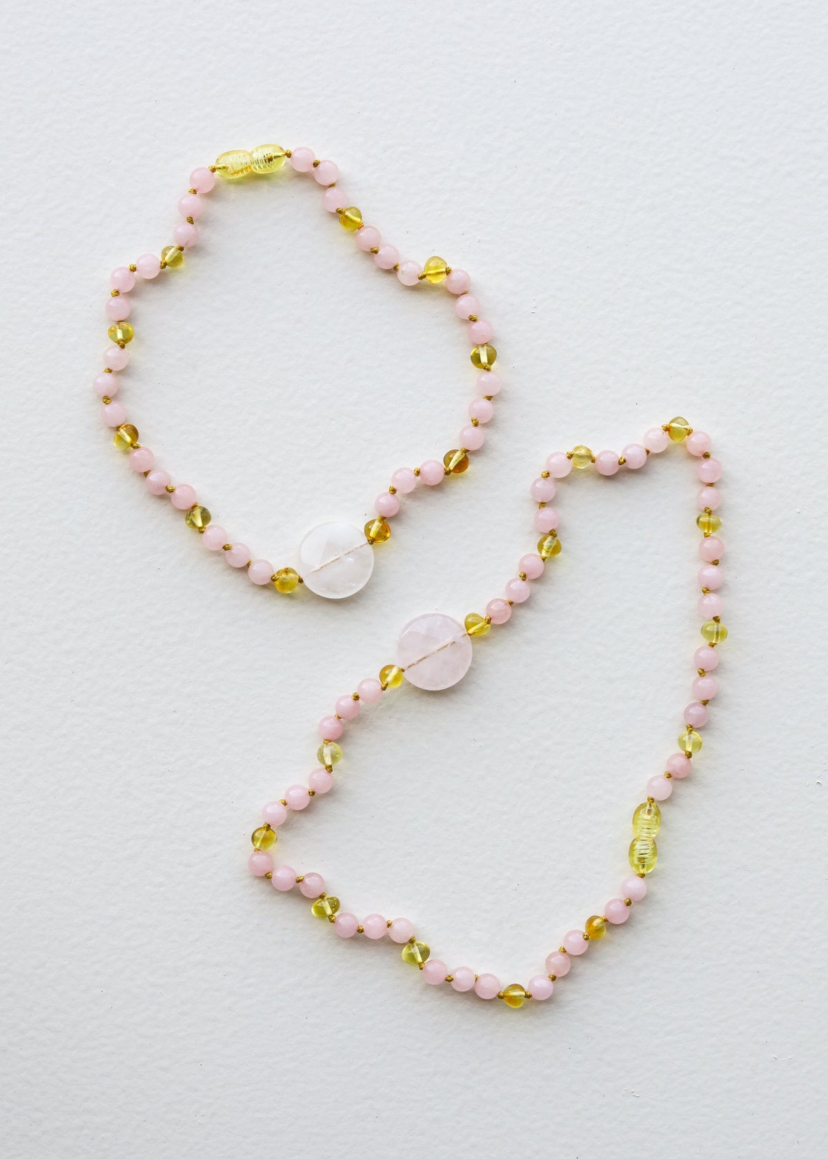 Stone bead necklace set with pink beads and gold oval charms, rose quartz pendant