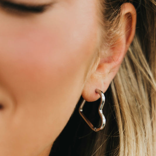 Silver-tone heart hoop earrings with open heart shape and hinged closure.