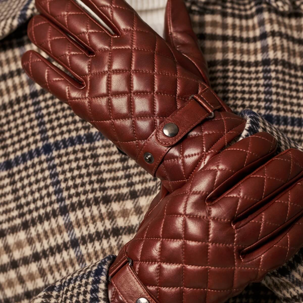 Brown quilted leather gloves with snap wrist strap and stitched diamond pattern