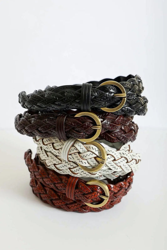 Stack of braided leather belts in black, brown, white, and rust tones with gold buckles