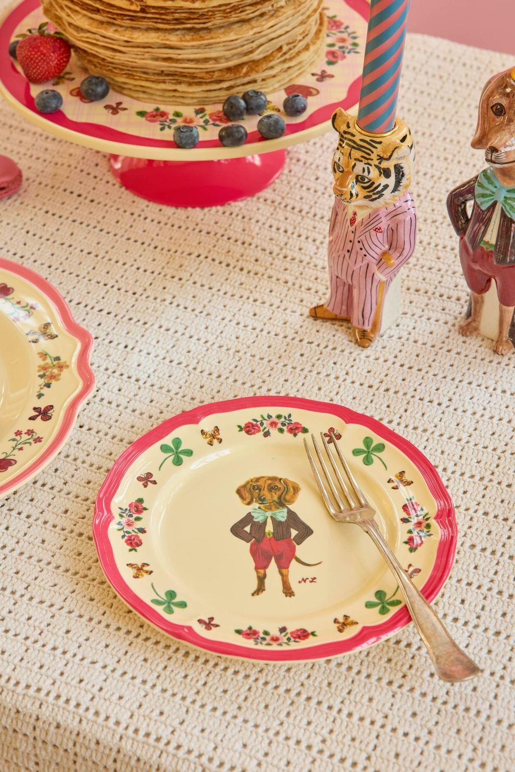 Melamine side plate on table, cream center with red rim, dog illustration and flowers