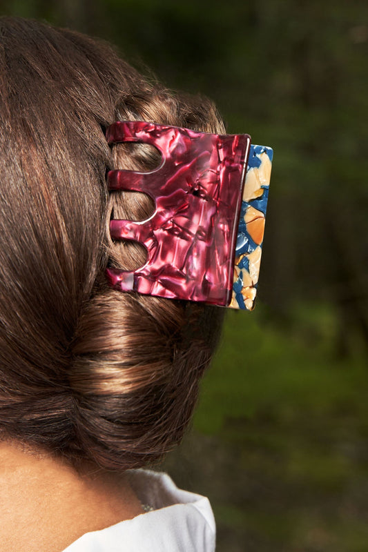 Resin hair claw clip in marbled blue and red on dark mane, five prongs
