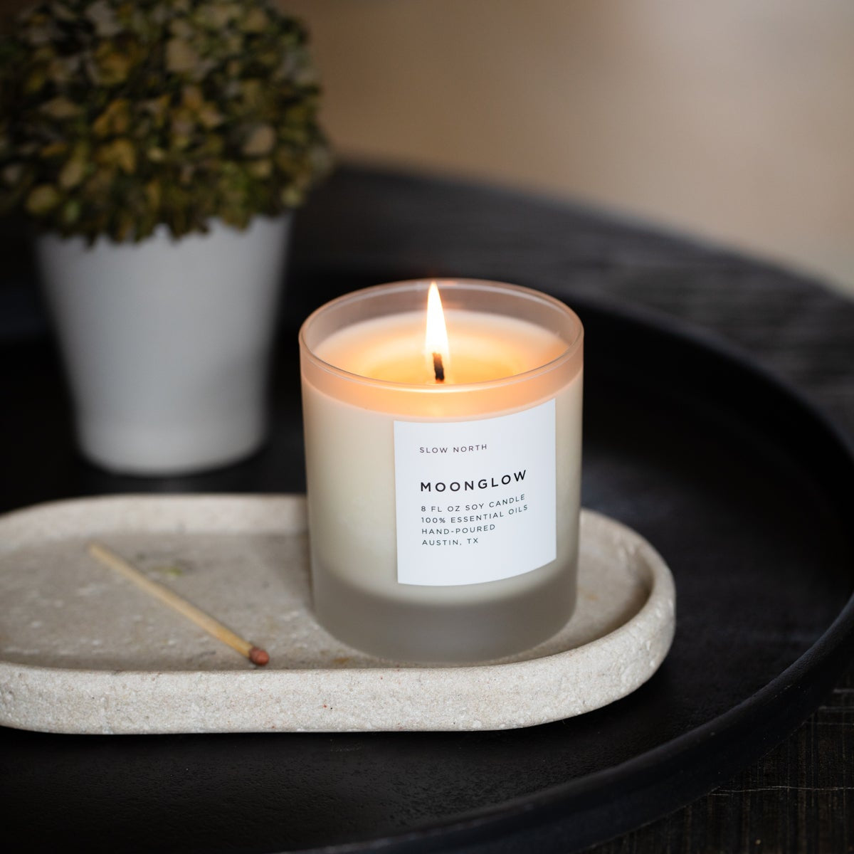 Lit Moonglow candle in a frosted glass jar with a white front label.