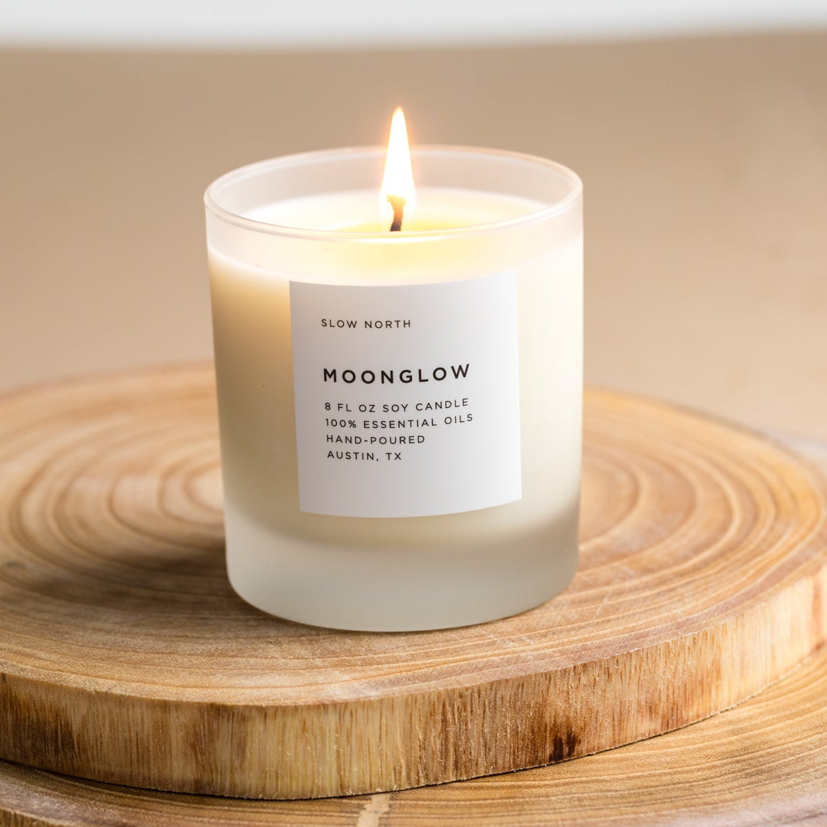 Moonglow soy candle in a clear frosted jar, lit, with a white label.