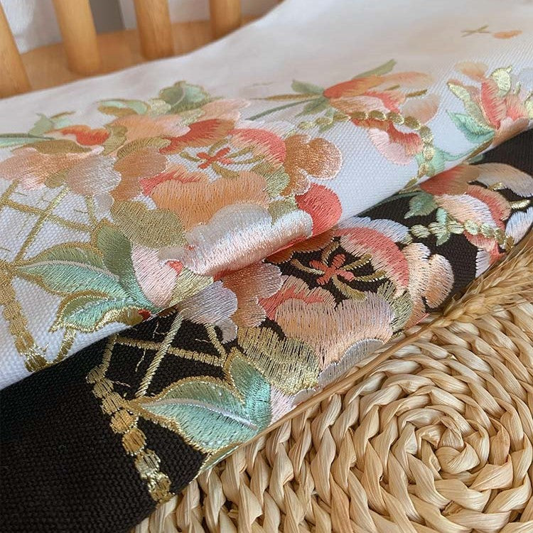 Close-up of floral embroidery on black tote bag with woven-style accents.