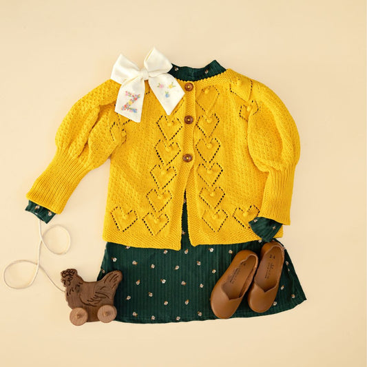 Light mustard knit cardigan with button front, diamond pattern, and long sleeves.