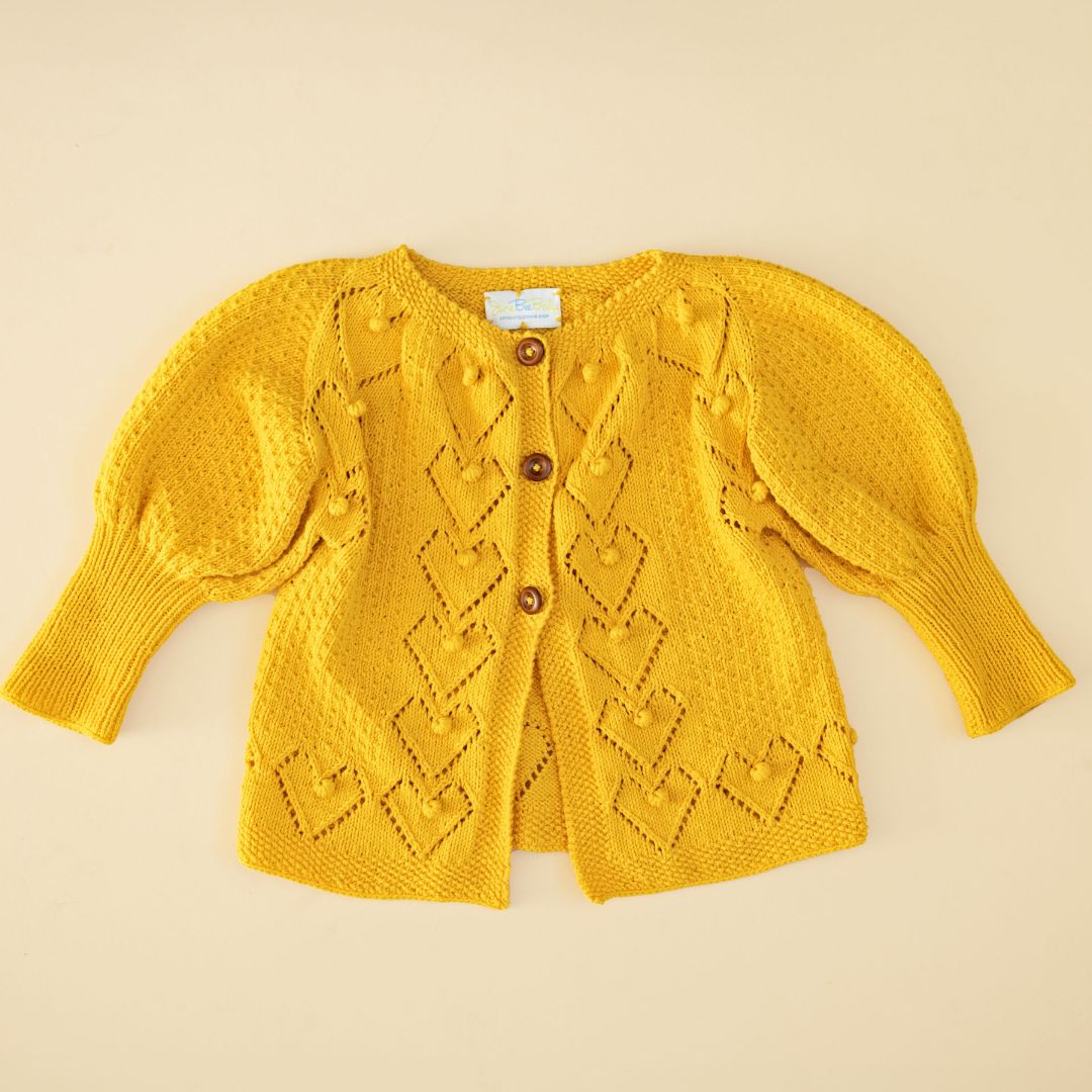 Yellow knit cardigan with button front, diamond pattern, and long sleeves.