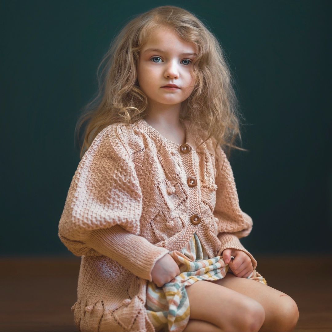 Blush knit cardigan with button front, textured diamond pattern, long puff sleeves.