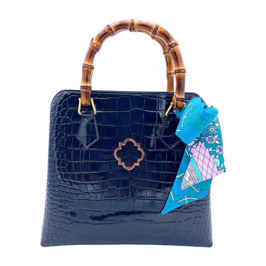 Marine blue croc-textured handbag with bamboo-style top handles and floral charm