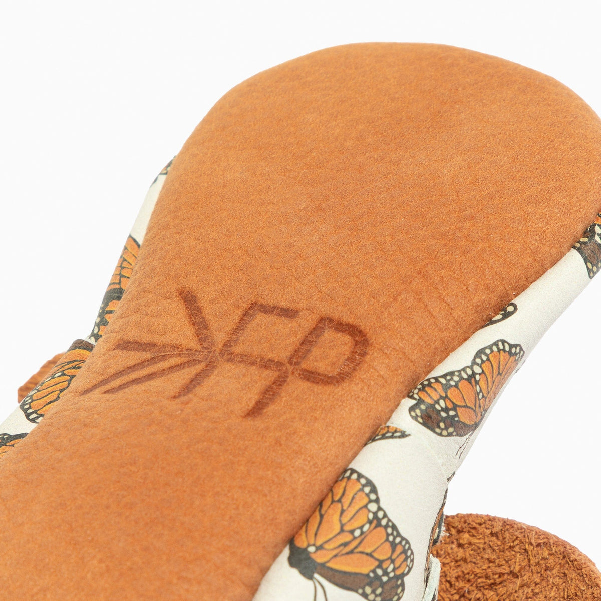 Cushioned sole of baby shoe with embossed FP logo and orange butterfly-printed lining