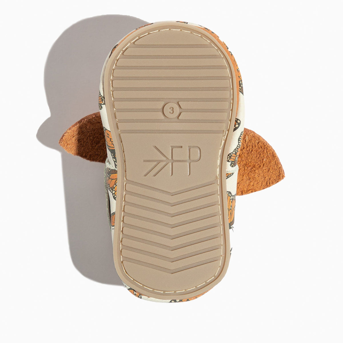 Rubber outsole bottom of baby shoes with tread pattern and monarch butterfly fabric edges