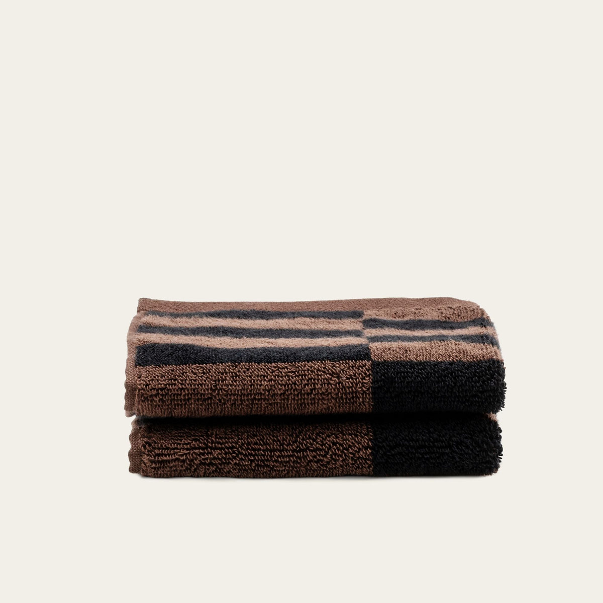 Two folded towels in tobacco brown and black plaid, compact square stack