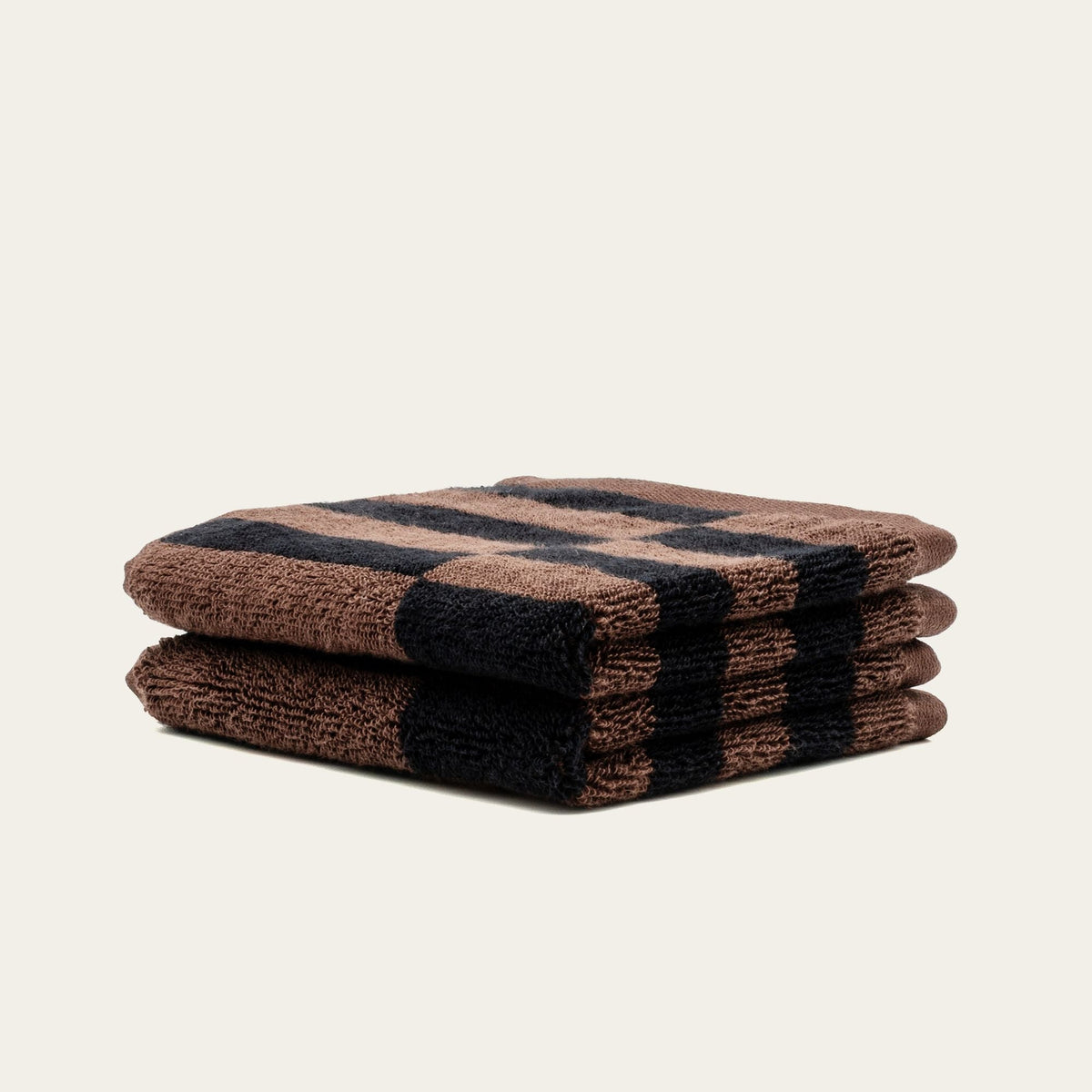 Stack of bath towels in tobacco brown and black plaid squares, neatly folded