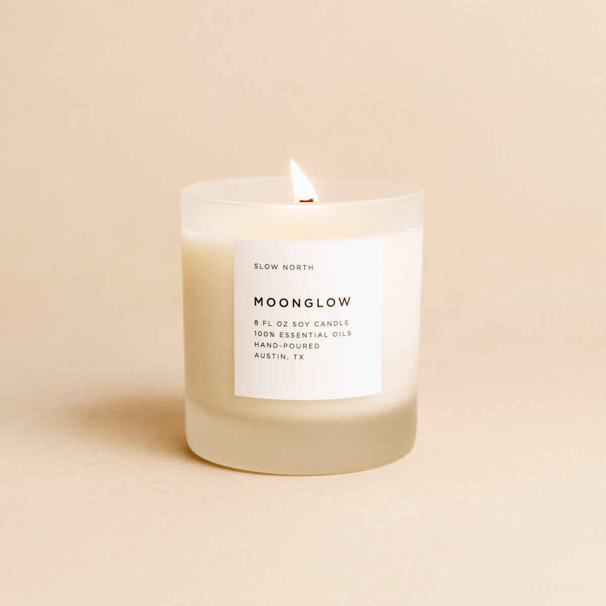 Lit Moonglow candle in a frosted glass jar with a white label.