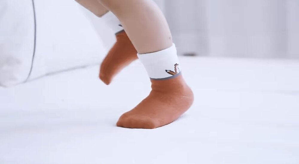 Toddler wearing orange fox socks with white cuff graphic