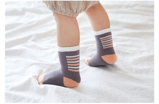 Kids crew socks on child feet with gray, pink, and white stripes and tan accents