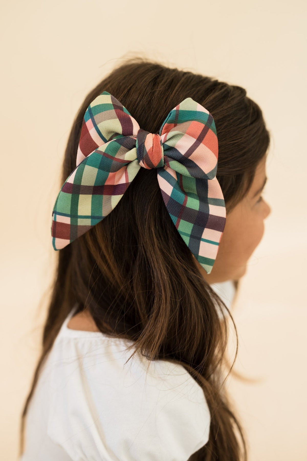 Plaid hair bow tied on hair, green and tan checks with navy and rust accents
