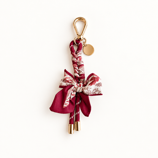 Burgundy scarf keychain with patterned bow and gold-tone clip and round tag