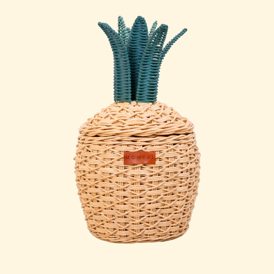 Small natural rattan storage basket shaped like a pineapple with green woven leaves