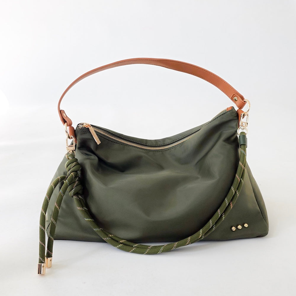 Olive green nylon slouchy shoulder bag with brown strap, rope tassels, and gold hardware