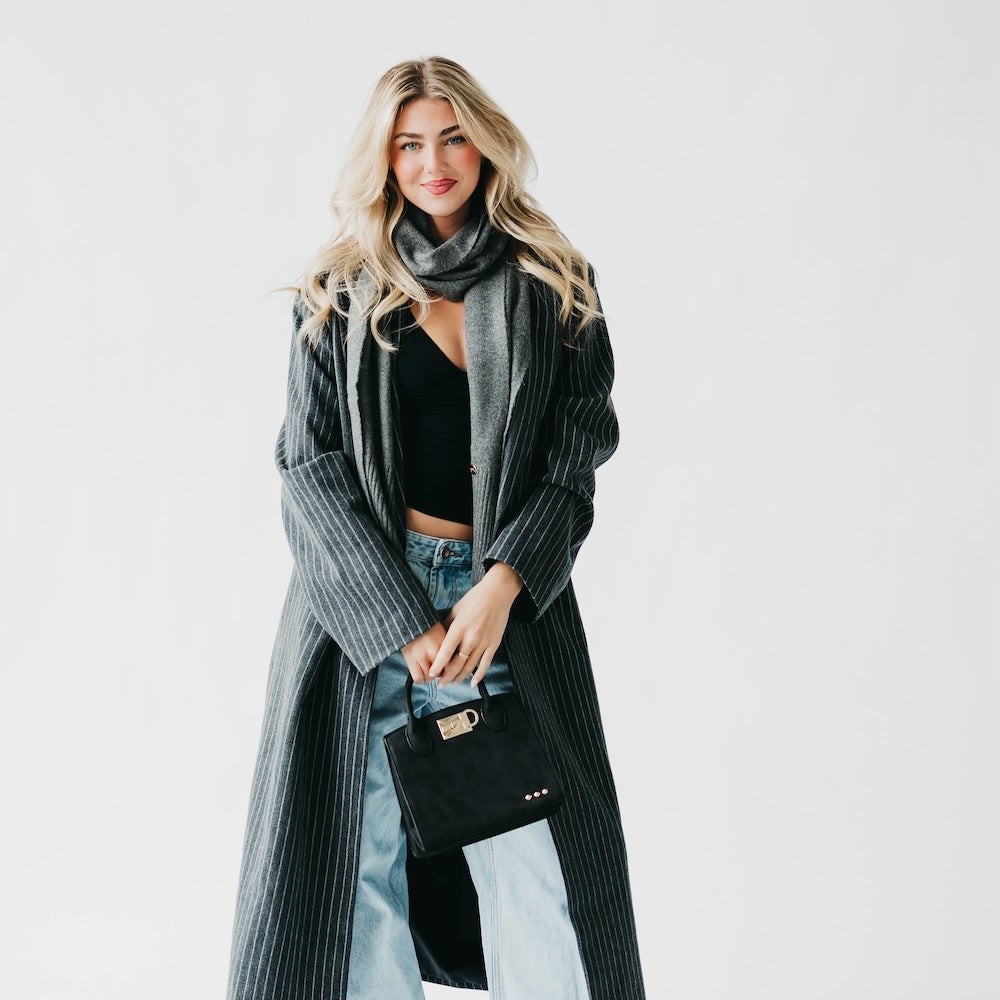 Black suede small tote bag with top handles, buckle clasp, and stud accents
