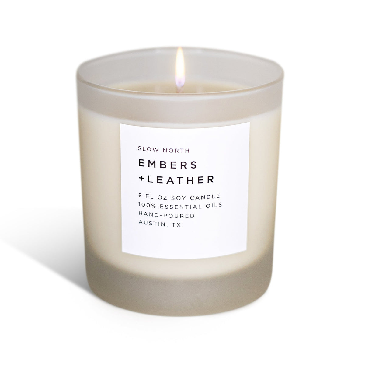 Lit Embers + Leather candle in a frosted glass jar with a white label.